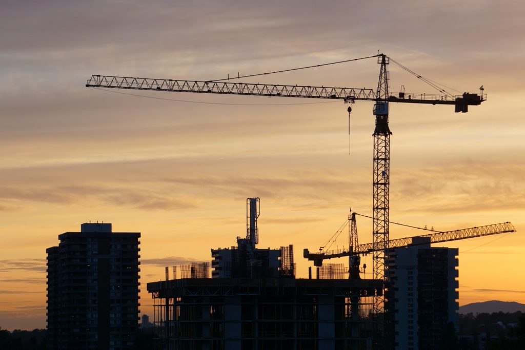 Silhouette of Crane Near High Rise Buildings during Sunset